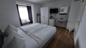 ein weißes Schlafzimmer mit einem Bett und einem Waschbecken in der Unterkunft Pension Schneider in Cochem