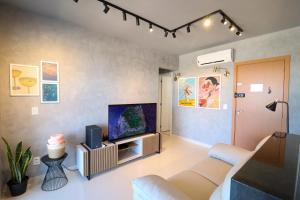 a living room with a couch and a flat screen tv at PALMAS EXPERIENCE - APARTAMENTO VISTA LAGO, próximo ao shopping in Palmas
