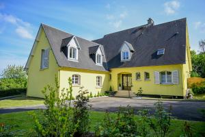 a yellow house with a black roof at La Fontaine Dort in Tessy-sur-Vire