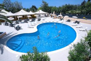 a pool at a resort with people swimming in it at Hotel Califfo in Quartu SantʼElena