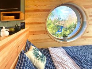 Un dormitorio con una ventana redonda y una cama en Bird Lodge am See mit Sauna für 6 Gäste, en Brzozie