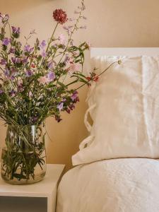 a vase of flowers on a table next to a bed at Appartamento il Rosmarino in Portoferraio