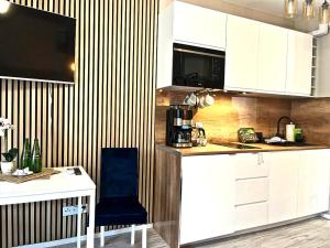 a kitchen with white cabinets and a blue chair at Blue Baltic & SPA in Dziwnów