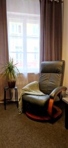a leather chair sitting in front of a window at Przytulny prywatny pokój w ścisłym centrum Warszawy Pokój 4 in Warsaw