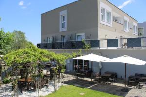 a patio with tables and umbrellas in front of a building at Ewitsch 13 - Hotel Garni in Berghausen