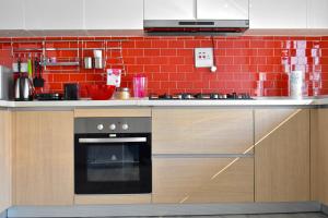 a kitchen with an oven and a red brick wall at Forefront Self-Catering Apartments in Kitwe
