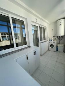 a white kitchen with a washing machine and windows at Piso vacacional con terraza panorámica a la ría. in Viveiro