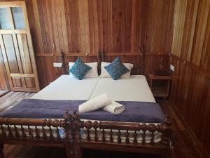 a bedroom with a bed with blue and white pillows at Sopanam Heritage Thekkady in Thekkady