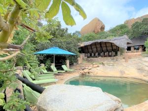 uma piscina com cadeiras e um guarda-sol num quintal em Big Cave Camp em Matopos