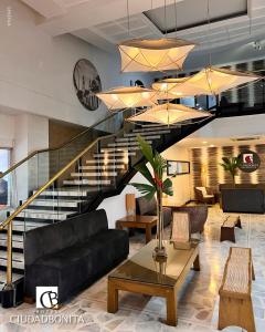 a living room with a black couch and a staircase at Hotel Ciudad Bonita in Bucaramanga