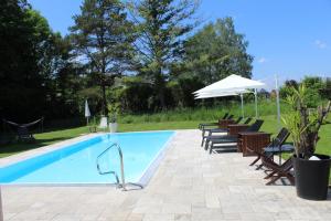 a swimming pool with chairs and an umbrella at Ewitsch 13 - Hotel Garni in Berghausen