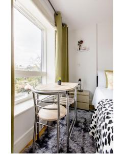 a room with a table and a bed and a window at Charlotte Double Room in London