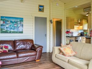 a living room with a leather couch and a kitchen at Rockhall - Souter Johnnies Cabin in Collin
