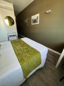 a bedroom with a large white bed with a green blanket at Hotel Alpes Cevennes in Guilherand