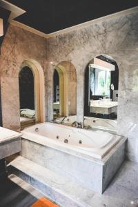 a large bathroom with a tub and a large mirror at La Fontaine Dort in Tessy-sur-Vire