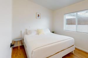 een witte slaapkamer met een wit bed en een raam bij Cherry Ave 3 2 in Tucson
