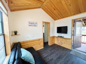 a living room with a couch and a flat screen tv at Sally's Cabin is a quaint two bedroom tiny home in Woodland Park