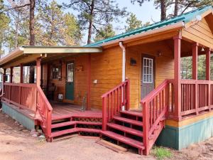 a wooden cabin with a porch and stairs to it at Sally's Cabin is a quaint two bedroom tiny home in Woodland Park