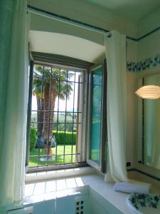 a bathroom with a window with a view of a palm tree at Galleria Imperiale Suites in Sarnico