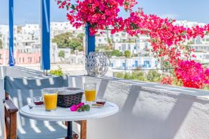 - une table avec deux verres de jus d'orange et des fleurs sur un balcon dans l'établissement Alpha Studios, à Náoussa