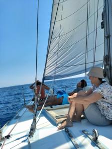 três pessoas sentadas num barco à vela no oceano em Cyclades sailing Experience em Finikas