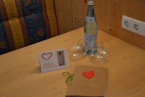 Una botella de cerveza y una tarjeta con dos corazones en una mesa. en Park Hotel Villa Etschland, en Plaus