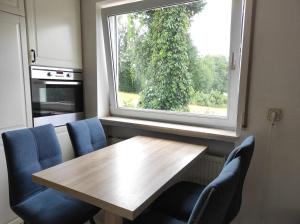 uma cozinha com uma mesa de madeira e cadeiras azuis e uma janela em Apartment im Grünen, nähe A7, Legoland, 2 Schlafzimmer em Vöhringen
