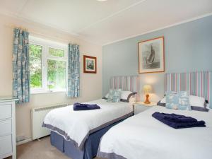 two beds in a room with two windows at Sweets Close in St Austell