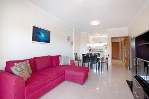 een woonkamer met een rode bank en een eetkamer bij Yara Beach Apartments T1 in Albufeira