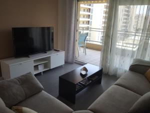 a living room with a couch and a flat screen tv at Ático frente al mar con parking para 5 personas in Calafell