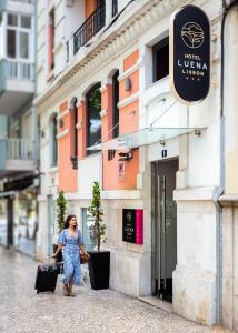 Una mujer caminando por una calle con su equipaje en Hotel Luena en Lisboa