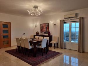 uma sala de jantar com uma mesa e cadeiras e um lustre em Villa do Outeiro em Figueira e Barros