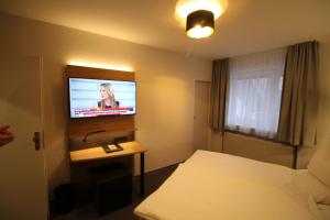 a hotel room with a bed and a flat screen tv at Gasthaus Bonneberger Hof in Vlotho