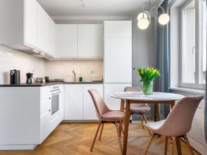 kuchnia z białymi szafkami oraz stołem i krzesłami w obiekcie Tyzenhauz Apartments Rakowicka Street w Krakowie