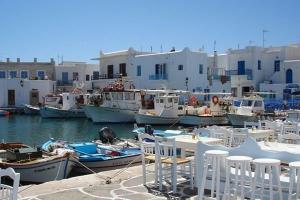 a group of white chairs and boats in a harbor at HOUSE 3Bedroom Maisonette ΕΞΟΧΙΚΟ Alyki PAROS 50m from BEACH ideal for families in Aliki +16 photos