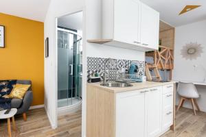 - une cuisine avec des placards blancs et un lavabo dans la chambre dans l'établissement La Cabane Urbaine, à Brest
