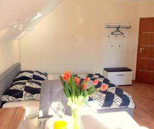 una habitación con una cama y un jarrón de flores sobre una mesa en Apartamenty Nad Jeziorem, en Postawele