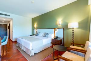 a bedroom with a white bed and a green wall at Puerto Antilla Grand Hotel in Islantilla