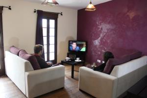 two people sitting on chairs in a living room watching tv at El Casino de Santa Cruz in Santa Cruz de la Sierra
