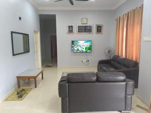 ein Wohnzimmer mit einem Sofa und einem TV in der Unterkunft Bella Homestay Perlis in Arau