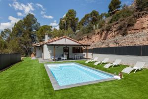 una piscina en un patio con sillas y una casa en Les Roques, en Castellnou de Bages