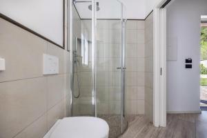 La salle de bains est pourvue d'une douche en verre et de toilettes. dans l'établissement Appartamenti Gaggiolo 2, à Dro