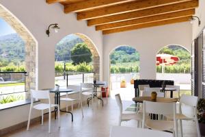 un restaurante con sillas blancas, mesas y ventanas en Antichi Ricordi - Il Pollaio, en Molino Nuovo