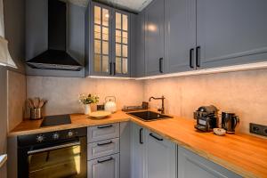 a kitchen with white cabinets and a wooden counter top at Arthouse Narnia in Liepāja
