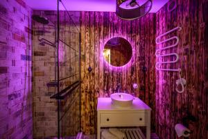a bathroom with a sink and a shower with purple lights at Arthouse Narnia in Liepāja