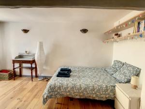 1 dormitorio con cama, mesa y escritorio en La maison aux volets bleus en Caunes-Minervois