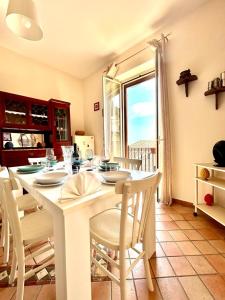 uma cozinha com uma mesa e cadeiras brancas e uma janela em Casa Amelia - Charme in Taormina em Taormina