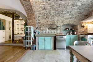 een keuken met groene kasten en een bakstenen muur bij Green Cactus House in La Spezia