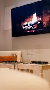 two wine glasses sitting on a wooden table with a tv at Suite de Luxe Jacuzzi balnéo,King size Bed in Collobrières +21 photos