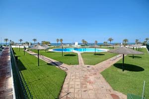 a resort with a swimming pool and umbrellas at Apartamento primera línea in Chiclana de la Frontera